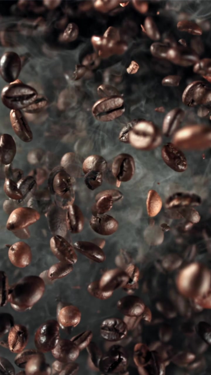 Chicchi di caffè tostati in caduta al rallentatore con fumo