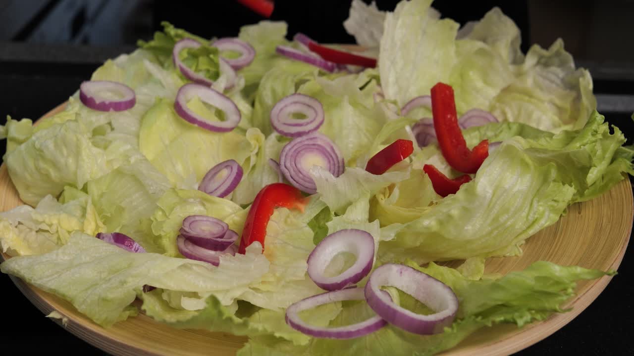 primer plano de mano de preparar una deliciosa ensalada con cebolla, pimientos y otras verduras adornadas por la mano de una mujer