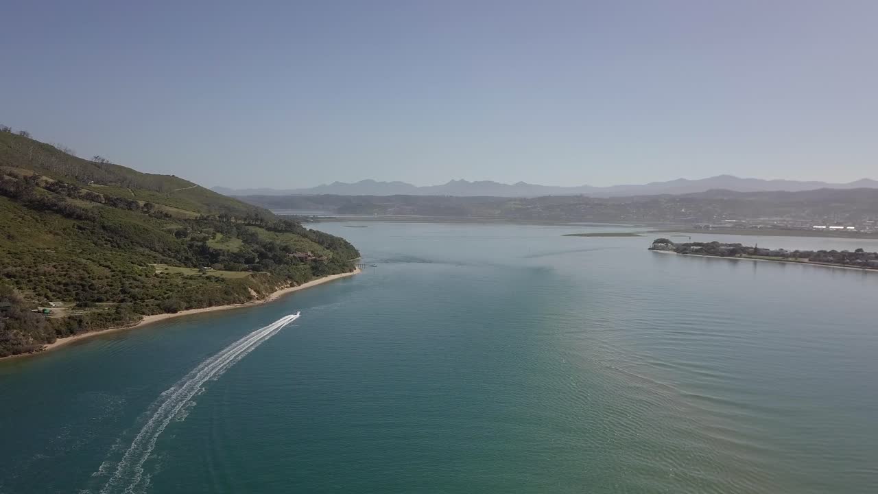 스피드 보트가 물 속에서 하얀 웨이크를 자르면서 knysna 석호의 높은 공중