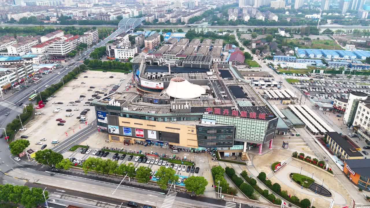Aerial view of the largest glasses shopping mall in Danyang, Jiangsu Province, China. Showcasing its expansive layout and modern architecture amidst bustling urban surroundings.