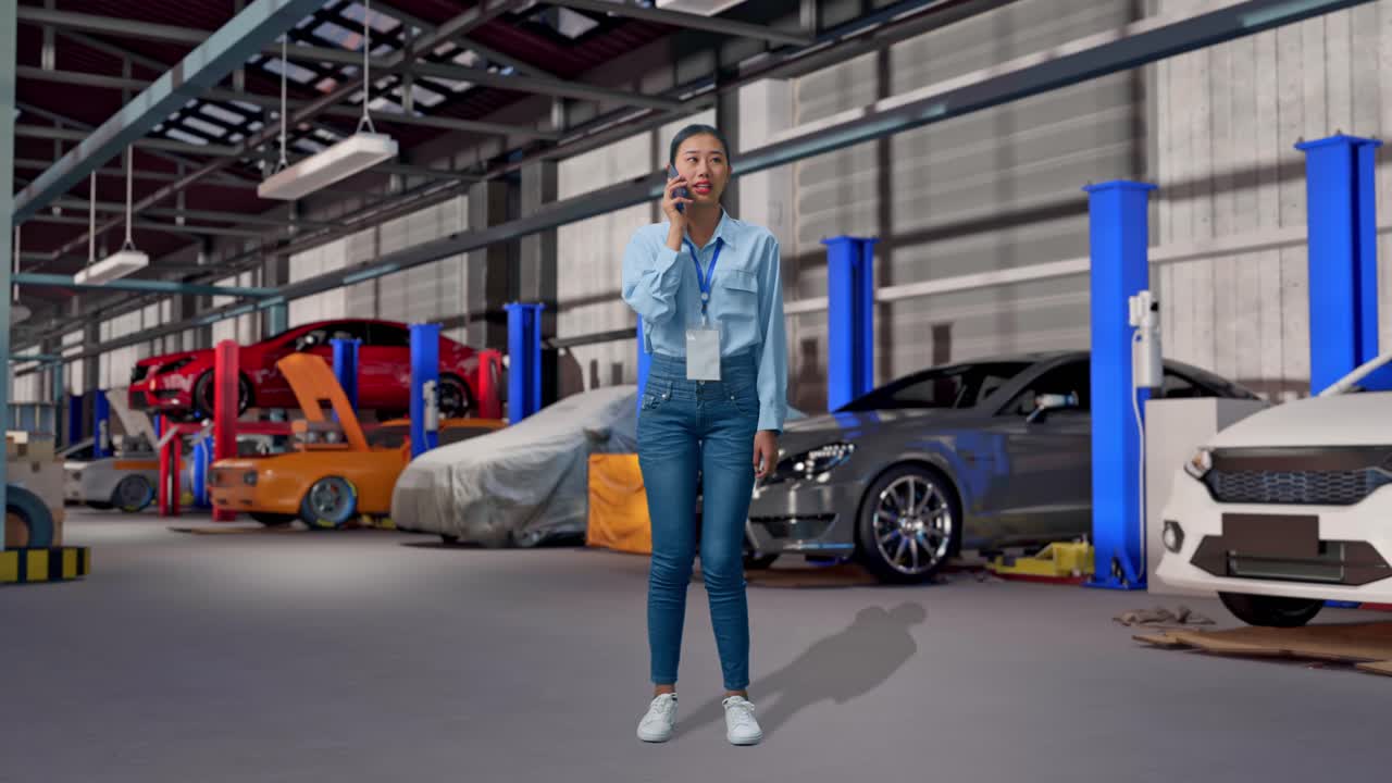 Corpo inteiro de uma mulher asiática em uma oficina de conserto de carros, ela está falando com alguém ao telefone