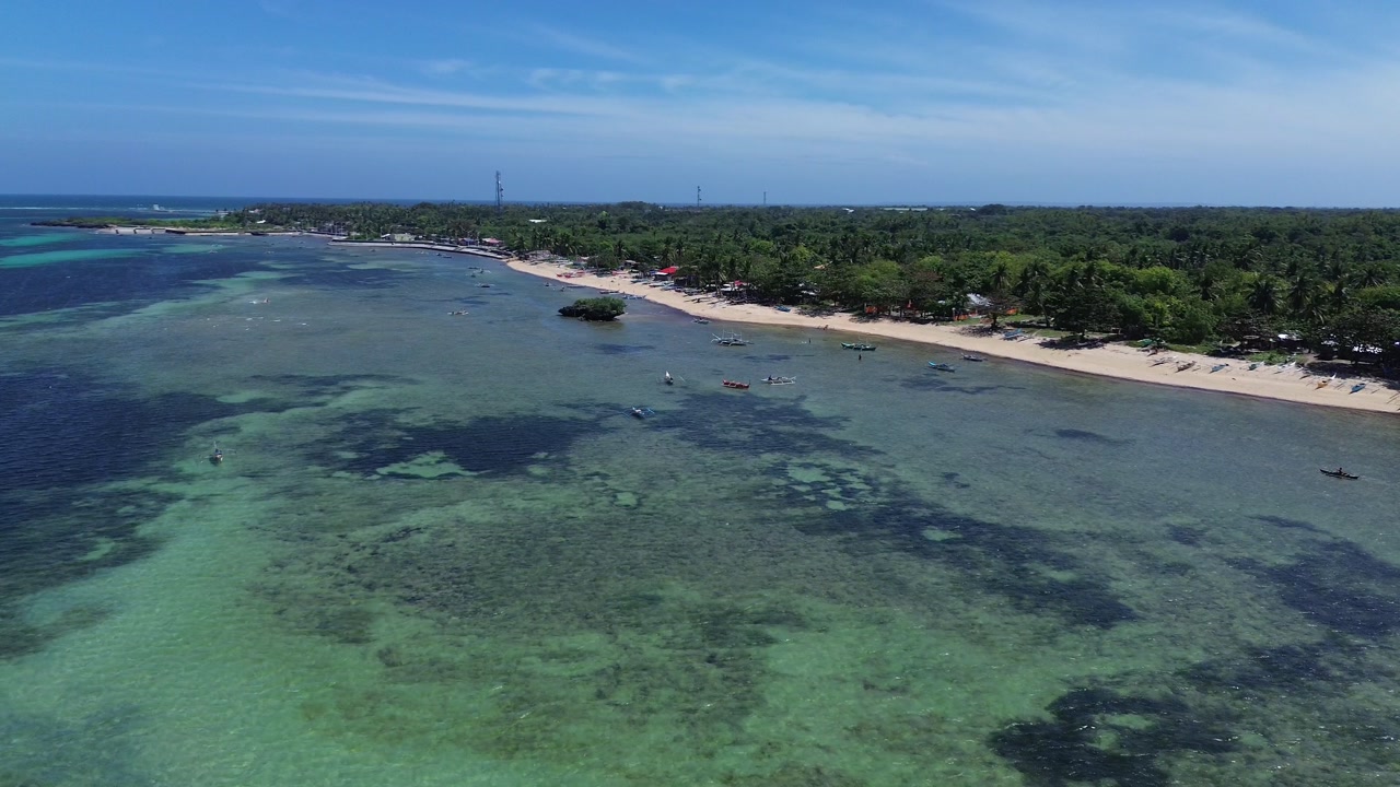 Aerial view of a tropical island coastline with white sand beach clear ocean water and dense green vegetation creating a pristine and untouched landscape on Bantayan Island Philippines Southeast Asia