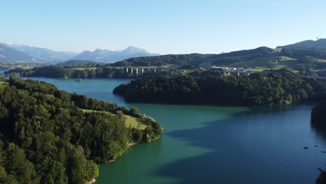 Vista-Sobre-El-Imponente-Lac-De-Gruyere-Con-Un-Puente-De-Autopista-Y-Las-Montañas-Suizas-En-El-Fondo,-Luz-Idílica-En-La-Noche