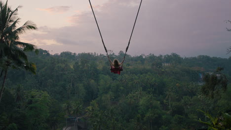 happy woman swinging over tropical jungle at sunrise travel girl enjoying exotic vacation sitting on swing in having fun holiday lifestyle freedom 4k