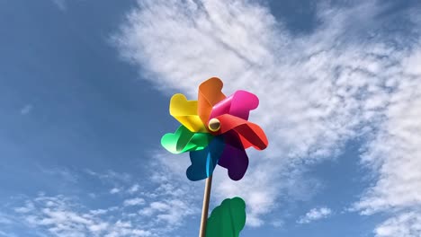 multicolored pinwheel rotates against a cloudy sky.