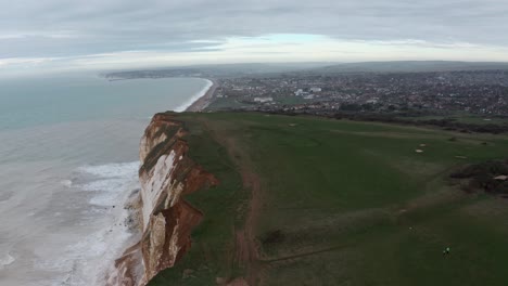 toma de drones en ascenso de acantilados blancos mirando hacia seaford village, inglaterra