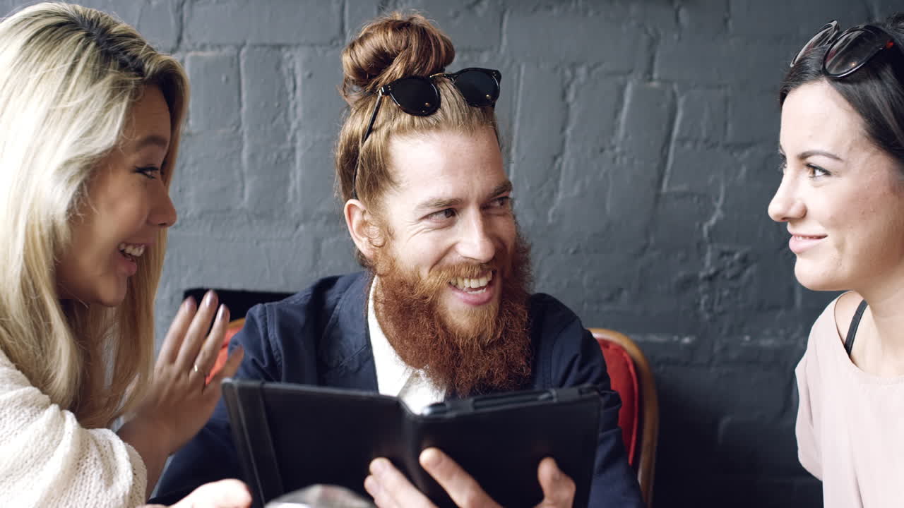 Venner slapper av på kafé og bruker digitalt nettbrett.