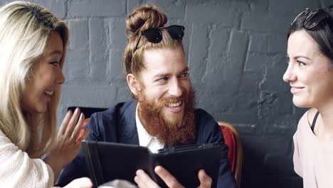 friends hanging out using digital tablet touchscreen in cafe