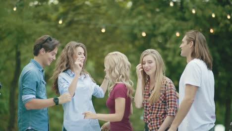 happy friends dancing, having fun and enjoying party outdoors.