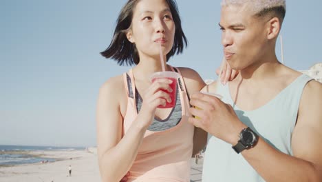 happy biracial couple drinking juice on promenade, in slow motion