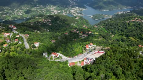 Perspectiva-Aérea-De-Residencias-En-La-Ladera-Del-Parque-Nacional-De-Gerês,-Portugal,-Con-La-Presa-De-Caniçada-Contra-Un-Cielo-Soleado,-El-Parque-Nacional-De-Peneda-Gerês