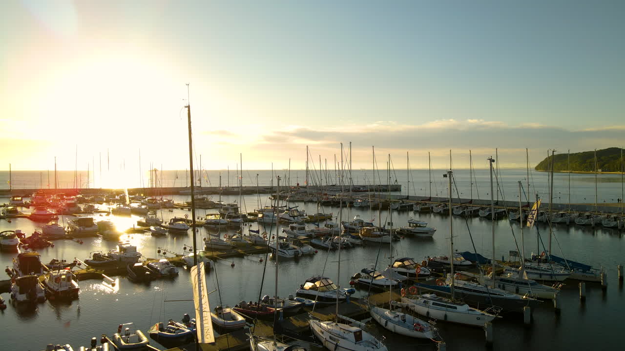 Lebhafte Sonnenlichtreflexion auf dem ruhigen Wasser der Danziger Bucht mit festgemachten Segelbooten im Stadthafen von Gdynia an der polnischen Ostseeküste