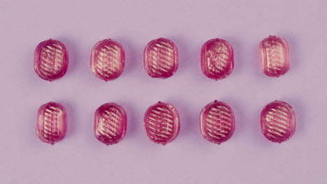 pink lollipops, candies, bonbons disappear on purple background. summer bright texture studio shot for store, supermarket, close up top view. children's favorite sweets made of sugar.