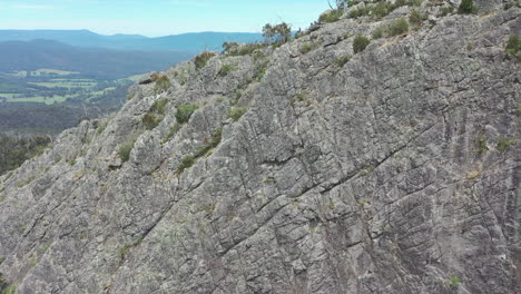 aerial approaches unique rock outcrop to reveal climbers on summit