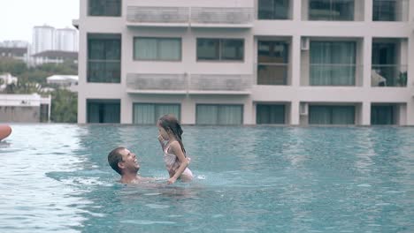 father-plays-with-daughter-in-clear-hotel-pool-slow-motion