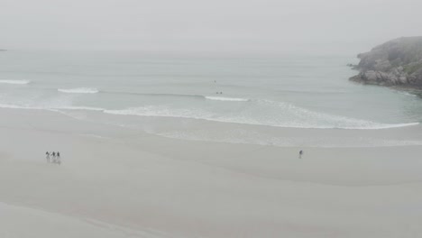 surfers and big waves on ceannabeinne beach on the scotland north coast 500 route which is the north sea