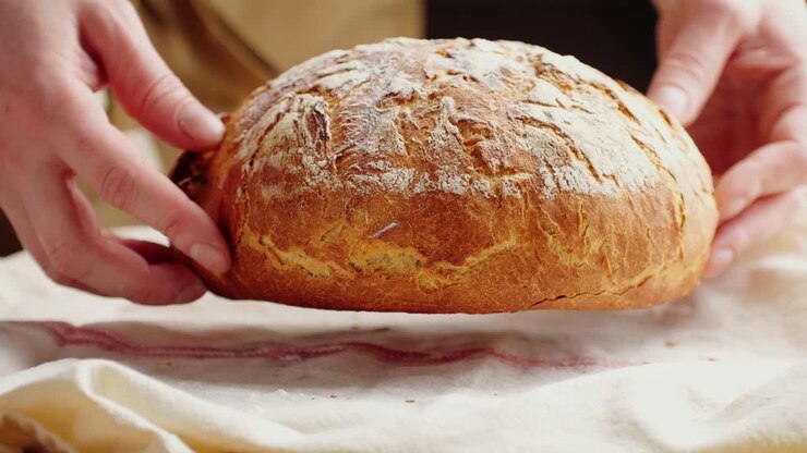 Hands holding a freshly baked loaf of bread