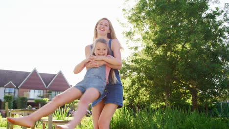 Madre-Jugando-Y-Balanceando-A-Su-Hija-En-El-Jardín-Del-Pub-De-Verano