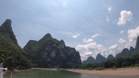 sightseeing boats sailing past the amous landmark high peak on the shore of the magnificent li river flowing from guilin to yangshuo, china