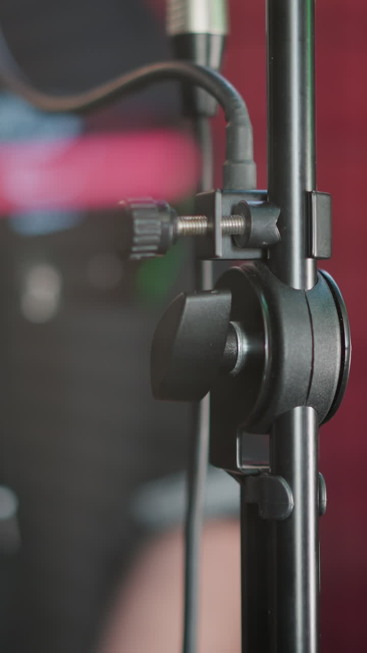 primer plano de un soporte de micrófono en una sala de estudio con luces de colores en el fondo. la imagen captura los detalles del equipo de audio en un entorno de grabación profesional