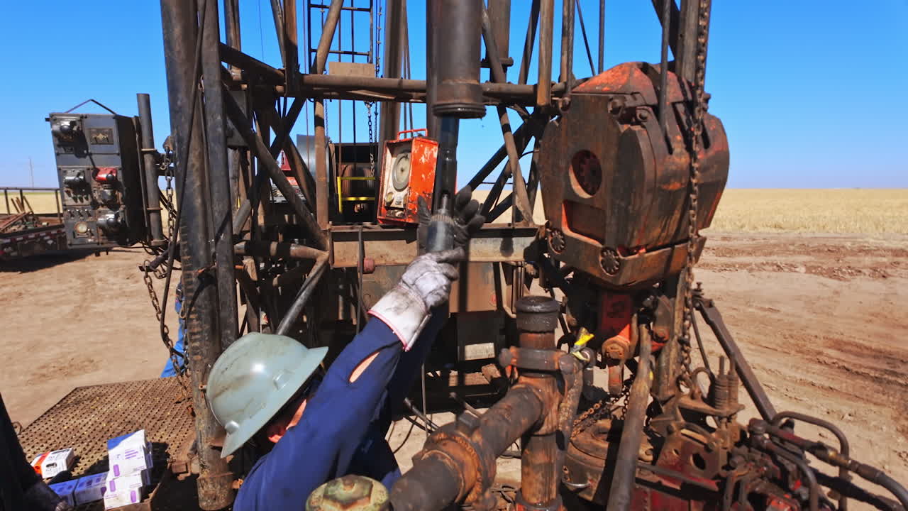 Workers' crew working at the site for natural resources production. Men in protective helmets arrange the equipment for oil or gas extraction.