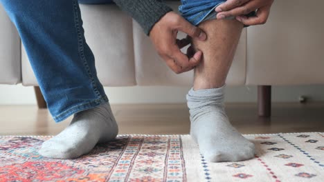 man sitting on sofa and checking his legs