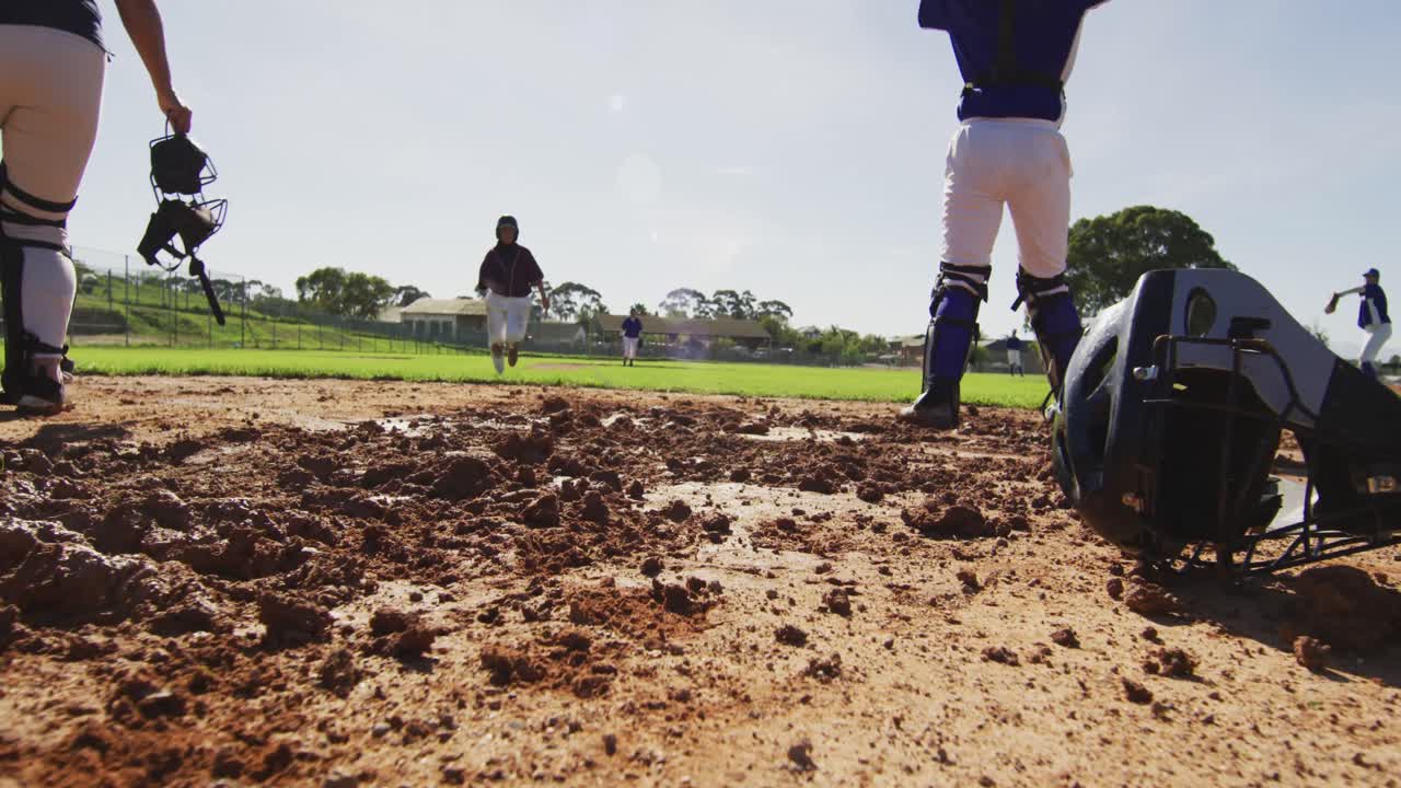 Diverse group of female baseball players, fielder attempting to catch running hitter at base
