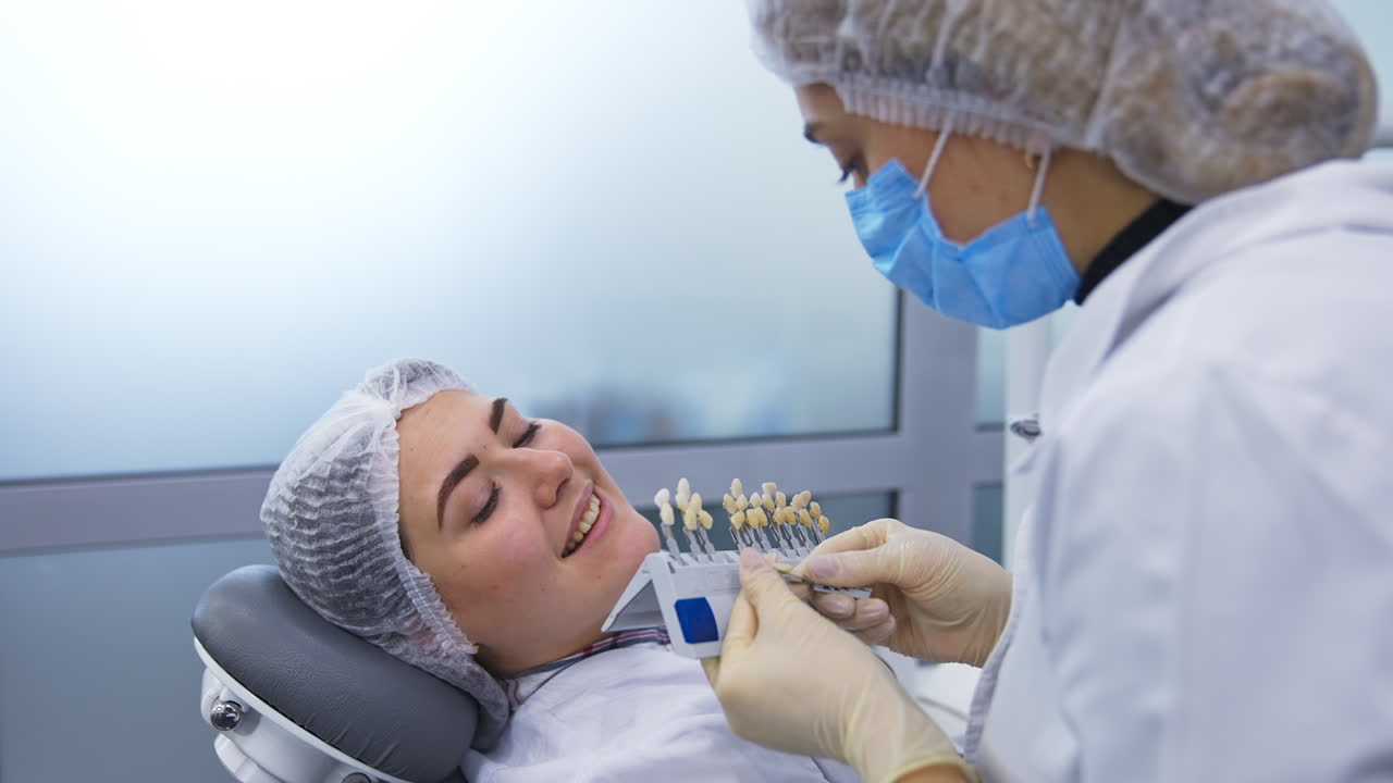 Female student holding the species of teeth of different shades. Future dentist chooses the most suitable tooth color for the patient.