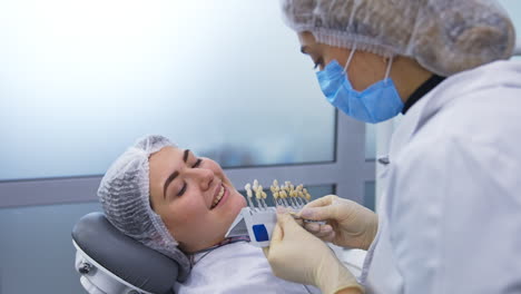 female student holding the species of teeth of different shades. future dentist chooses the most suitable tooth color for the patient.