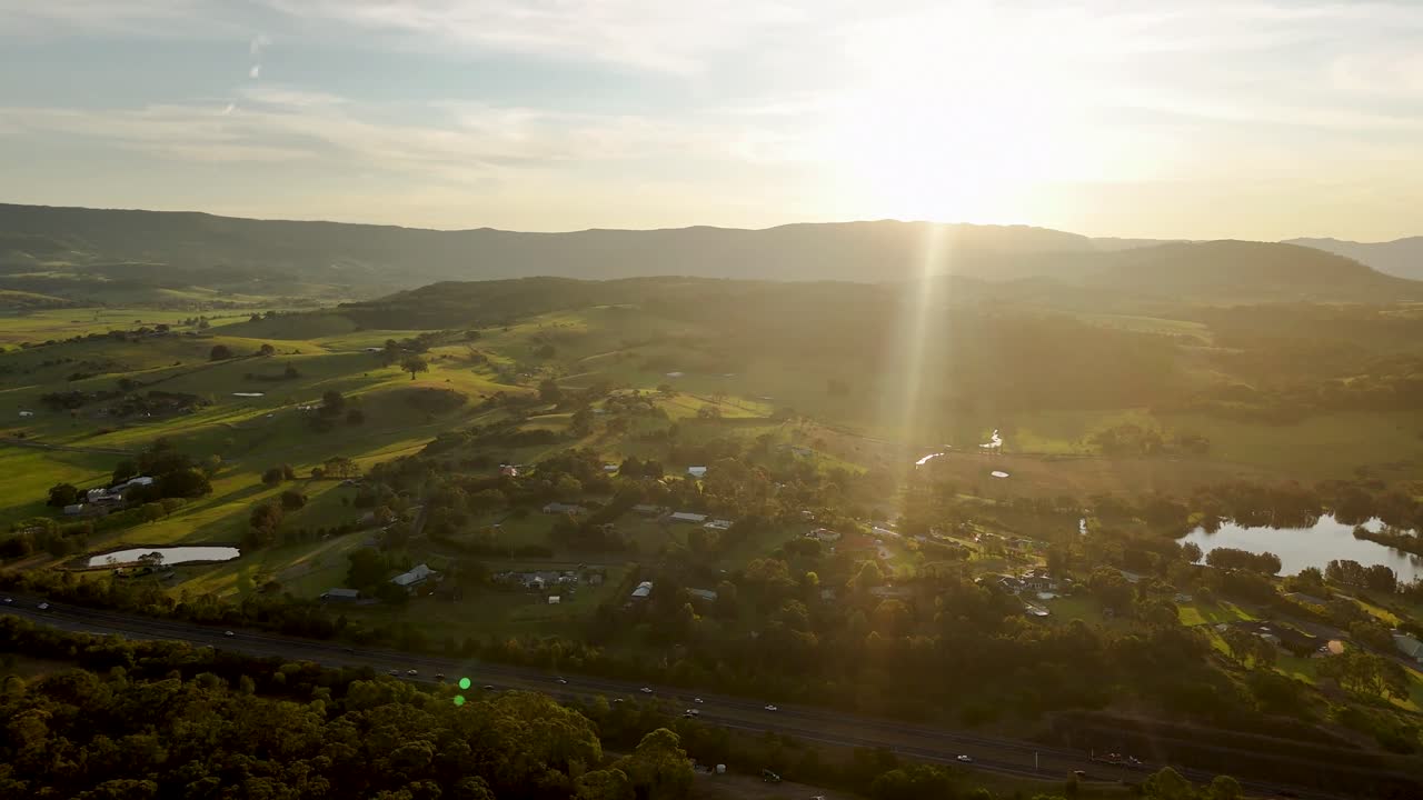 Aerial establishing orbit above Minnamurra, Australia, capturing a sunrise over lush landscapes and coastal scenery