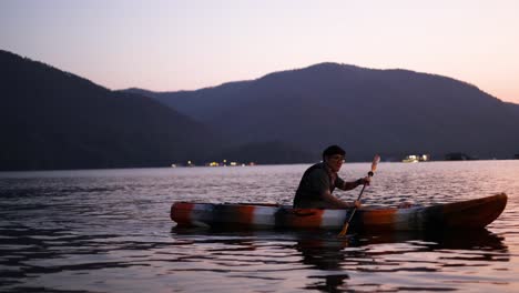 person kayaking on calm water at sunset