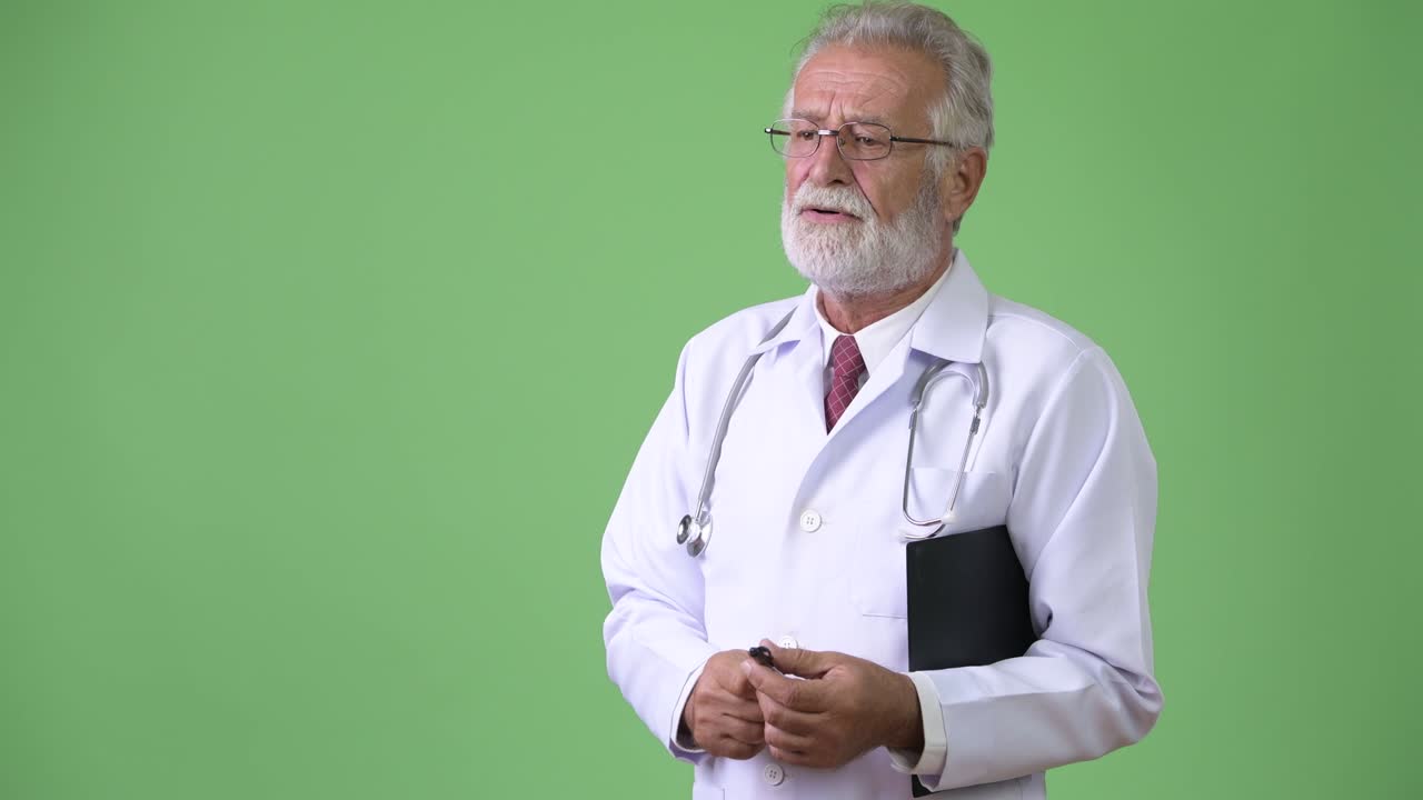 Médico sênior bonito e barbudo em fundo verde.