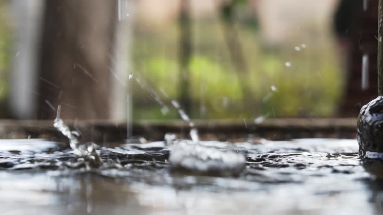 Drops of water falling into a fountain from the top in slow motion in Granada, Spain