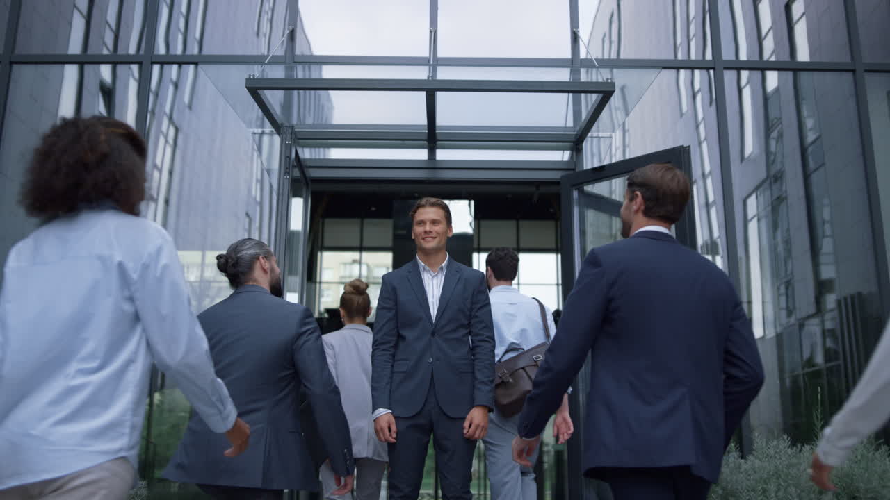 행복한 사업가가 사무실 문 앞에 서서 즐거운 직원들을 만난다.