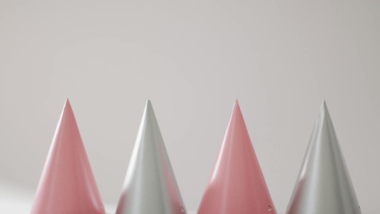 video de una fila de sombreros de fiesta rosados y plateados sobre un fondo gris pálido