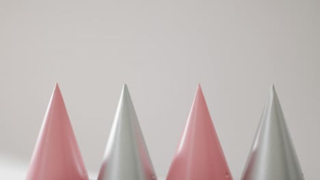 video of a row of pink and silver party hats on pale grey background