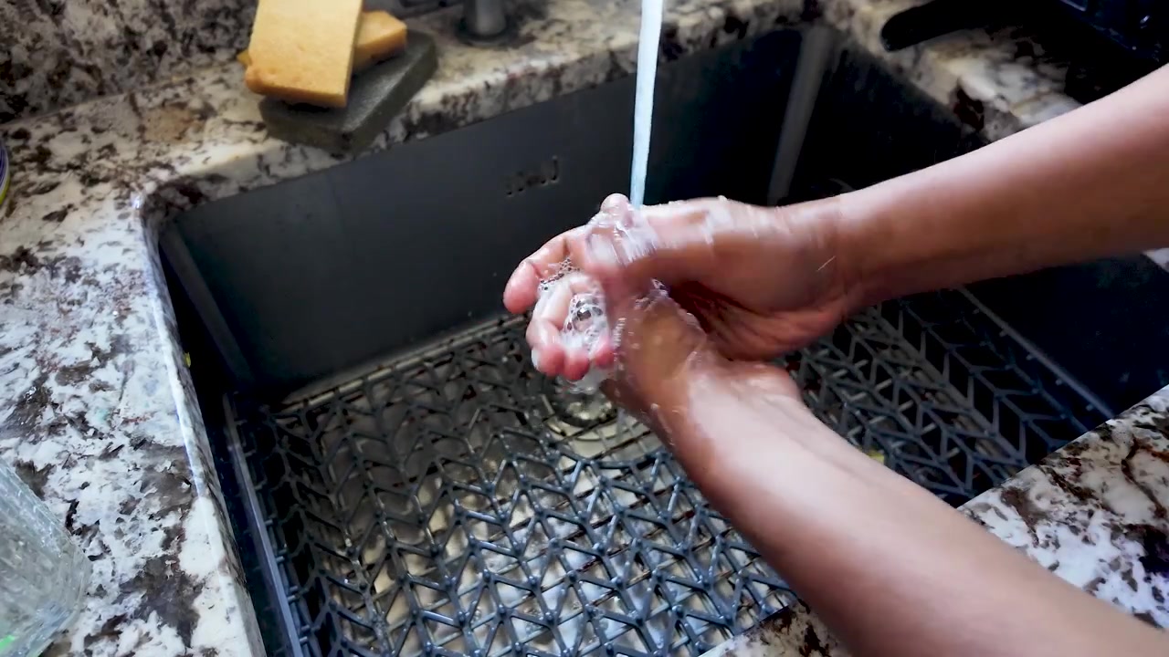 Higiene e saúde são conceitos fundamentais enquanto uma pessoa do sul da Ásia lava as mãos completamente sob água corrente em uma pia de cozinha. Esta ação promove saneamento e limpeza.