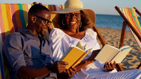 happy couple reading books on a beach at sunset