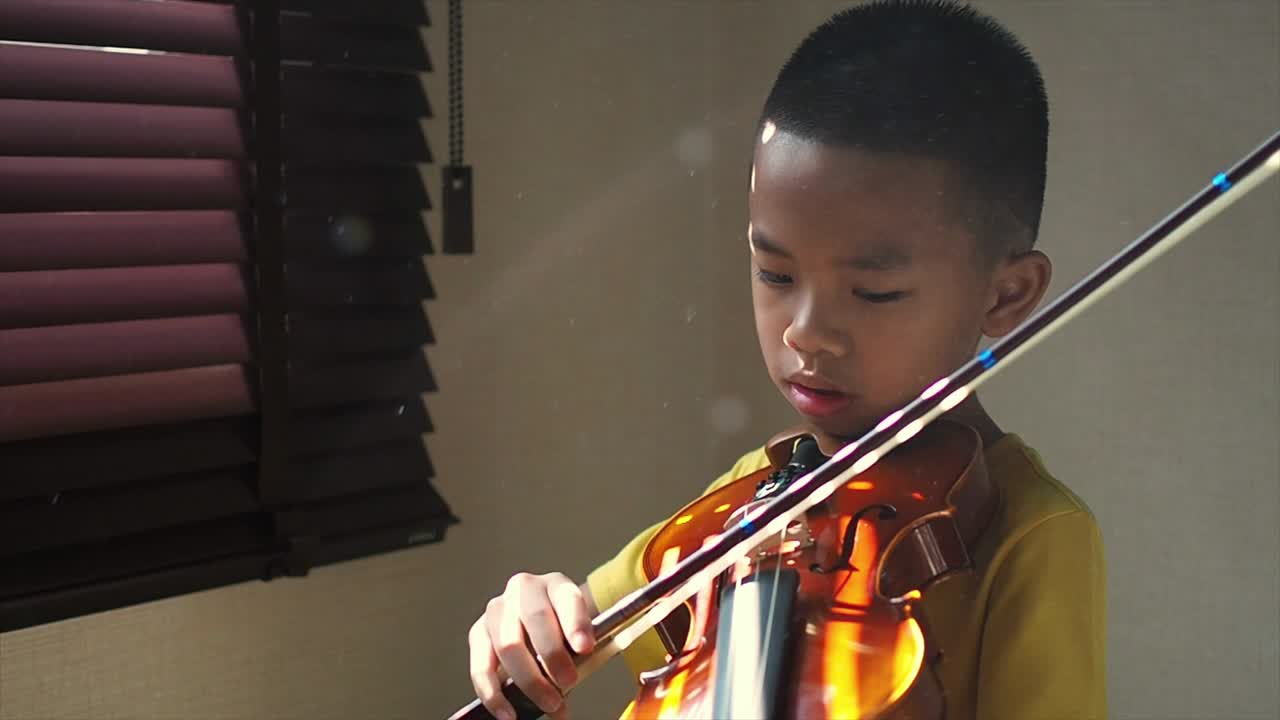 un chico asiático aprendiendo a tocar el violín.