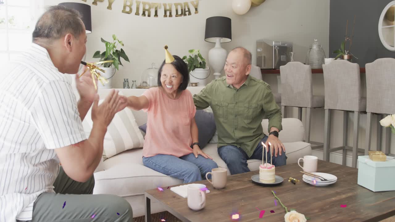 Confetti falling, mature man guiding senior woman hands toward cake, placing birthday hat, partying