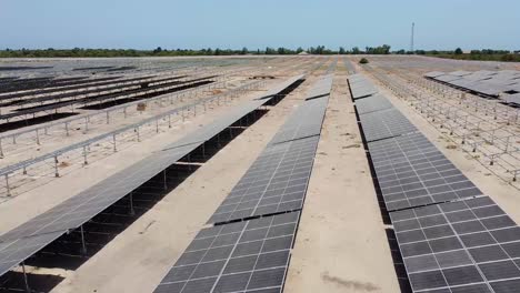 Aerial-sliding-left-view-over-dirty-and-dusty-bifacial-solar-panels-at-Jambur-solar-generation-project-site-under-construction---Gambia