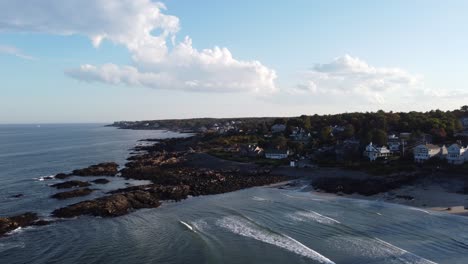 Aerial-coastline-view-of-Ogunquit-Maine-USA-,-drone-footage-of-waterfront-house-district-and-rocky-coast-during-sunny-day