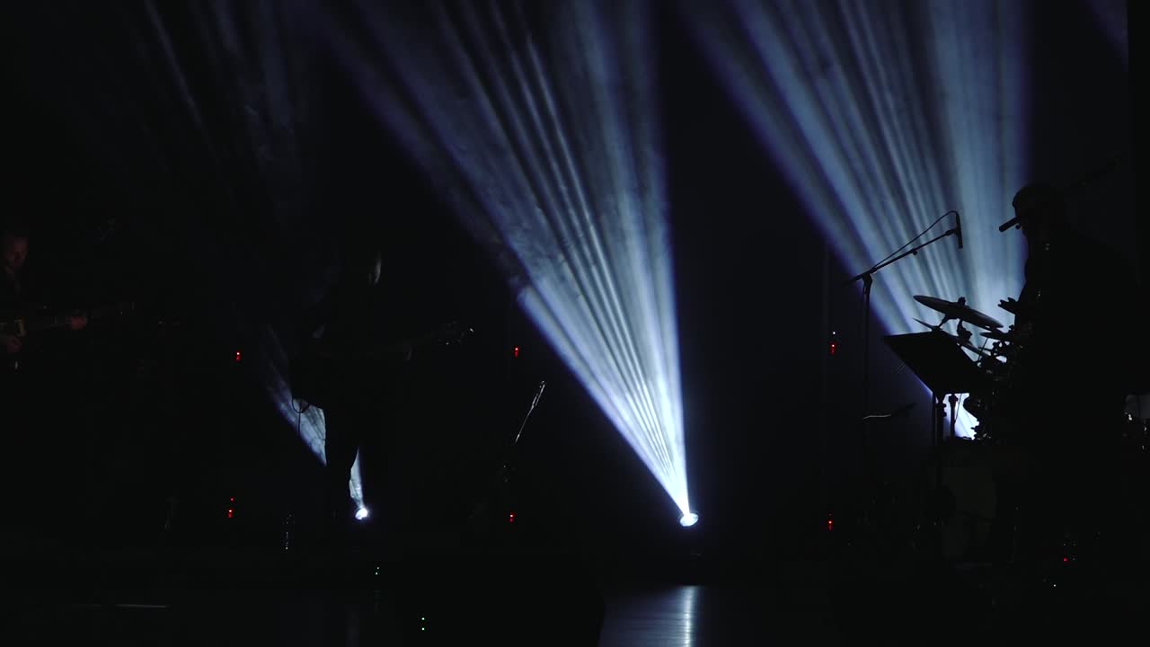 Multiple soft blue light beams stream diagonally through a dark environment, creating an ethereal, smoky atmosphere with visible texture and copy space