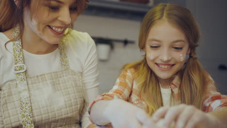 close up of the mother's and daughter's hands breaking an egg to the glass bowl with a daugh inside. portrait shot in the kitchen while cooking.