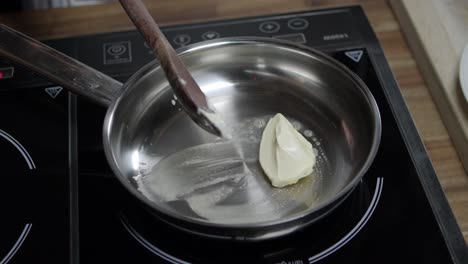 el chef agrega mantequilla con una cuchara en la sartén caliente para preparar la salsa de mantequilla de café de parís, en la estufa de inducción