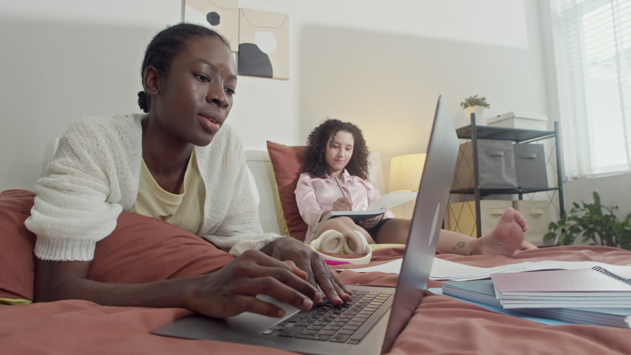 Friends Doing Homework in Bed at Home