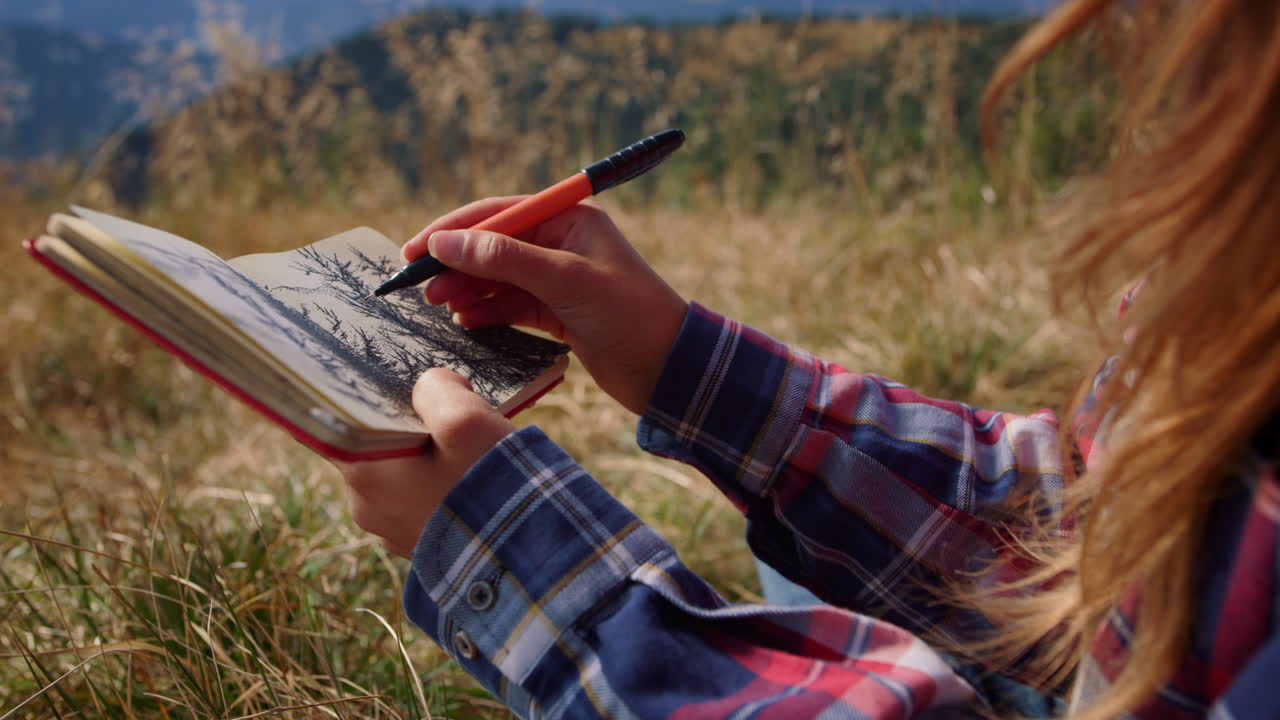 Woman hands drawing picture of trees in notepad