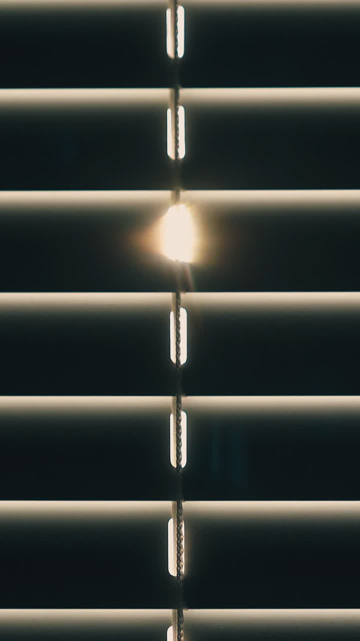 CU shot: motion down along modern closed horizontal window blinds against bright backlight in room at home extreme closeup