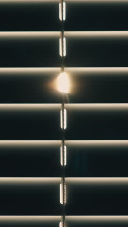 cu shot: motion down along modern closed horizontal window blinds against bright backlight in room at home extreme closeup