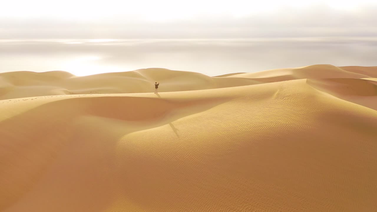 antena sobre una modelo femenina parada en las hermosas dunas de arena del desierto de namib en namibia con el fondo de la costa de los esqueletos 2
